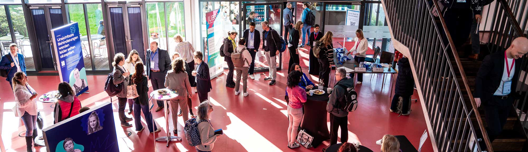Viele Menschen stehen in einem Foyer und unterhalten sich.