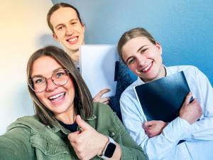 Drei junge Menschen lachen glücklich in die Kamera